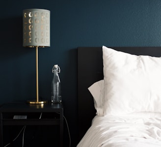 gray table lamp beside white bed pillow