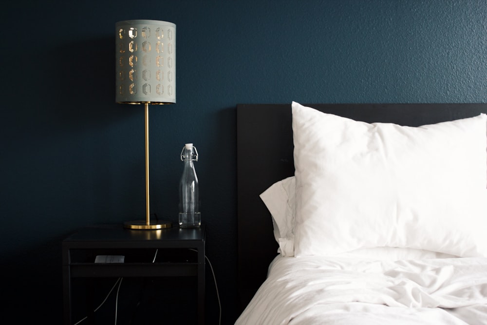 lámpara de mesa gris junto a la almohada de la cama blanca