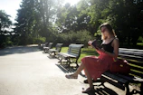Sunlit park bench with a novel resting beside a pair of reading glasses
