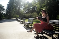 A sunny park bench with a paperback and reading glasses resting on it.