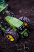 Close-up of a mini tractor's sturdy tires rolling through rich, wet soil ready for planting.