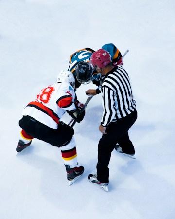 A hockey player skating with the puck during a practice session at an indoor rink