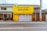 A small, yellow building labeled 'ペットハウス SANTA' stands alongside other buildings with traditional architecture. The structure appears to be a pet store with a dog silhouette in the window display. Several plants are placed near the entrance.