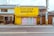 A small, yellow building labeled 'ペットハウス SANTA' stands alongside other buildings with traditional architecture. The structure appears to be a pet store with a dog silhouette in the window display. Several plants are placed near the entrance.