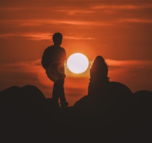 silhouette of two people looking at sunset