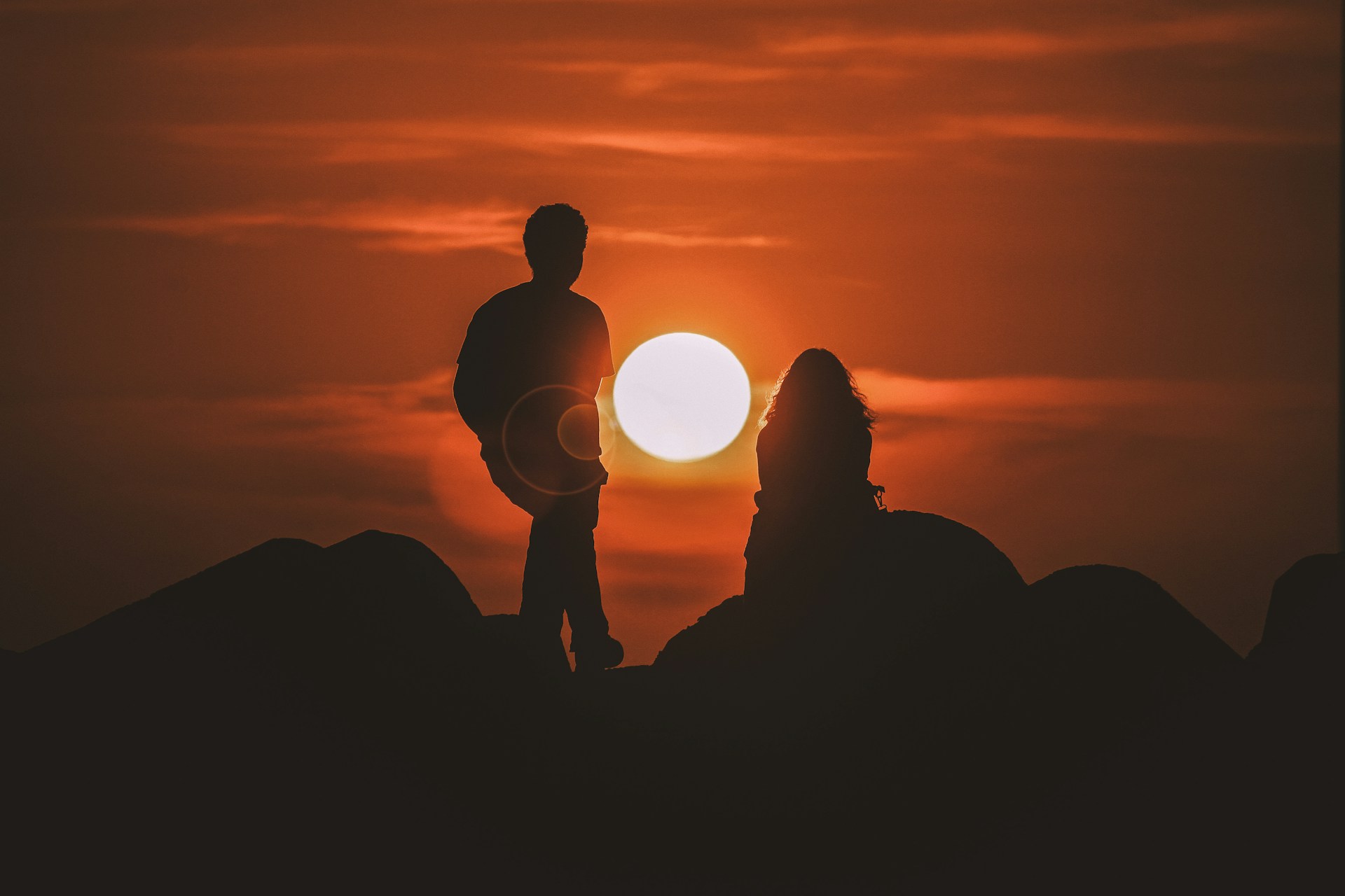 silhouette of two people looking at sunset