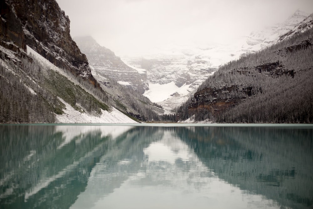 body of water near mountain covered by snow at daytime