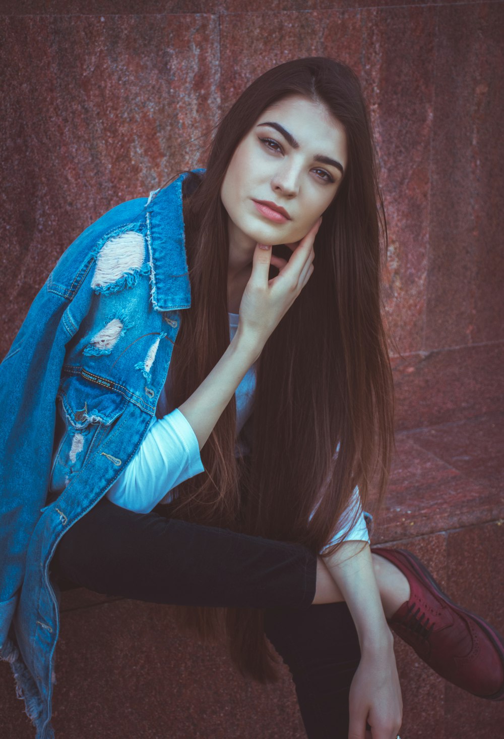 woman sitting while touching her left cheek