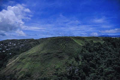A panoramic view of the lush green hills surrounding the Hilltop Eco Luxury Resort site at sunrise.