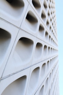Architectural detail of a villa’s geometric window patterns casting sharp shadows on white concrete walls.