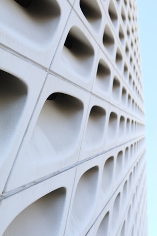 Architectural detail of a villa’s geometric window patterns casting sharp shadows on white concrete walls.