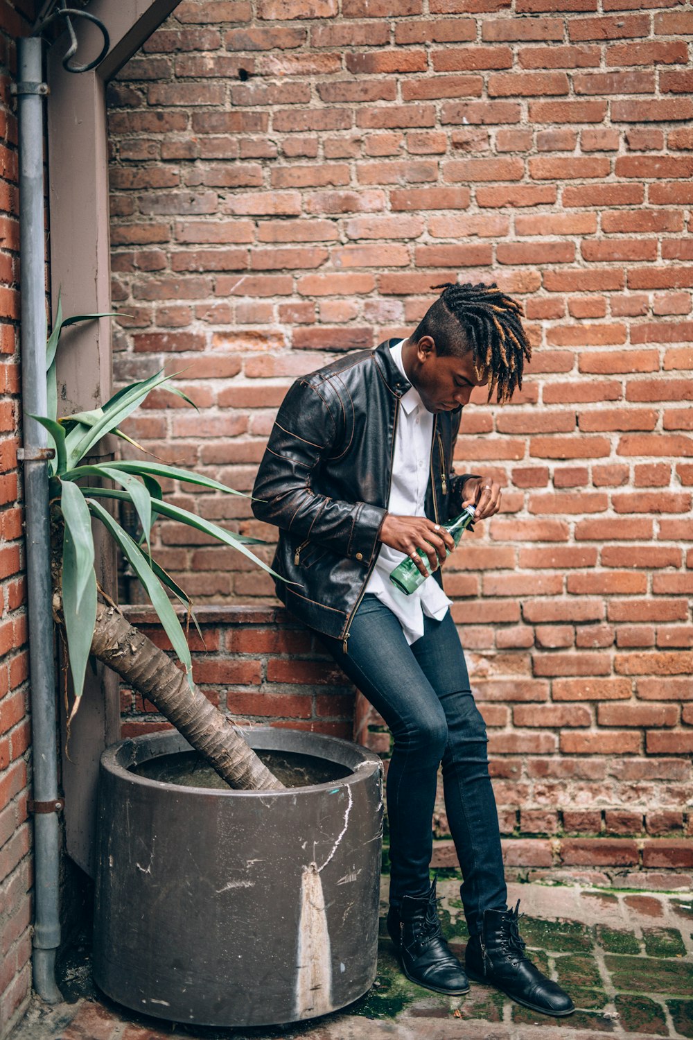 man holding green bottle near brown concrete wall