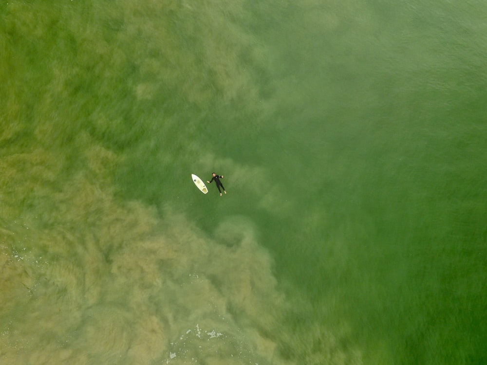aerial photography person floating at sea beside white board at daytime