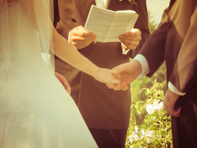 Soft warm-toned photo of a couple holding hands during a golden hour wedding shoot.