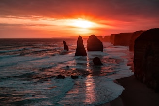 silhouette of stone on seashore during golden hour