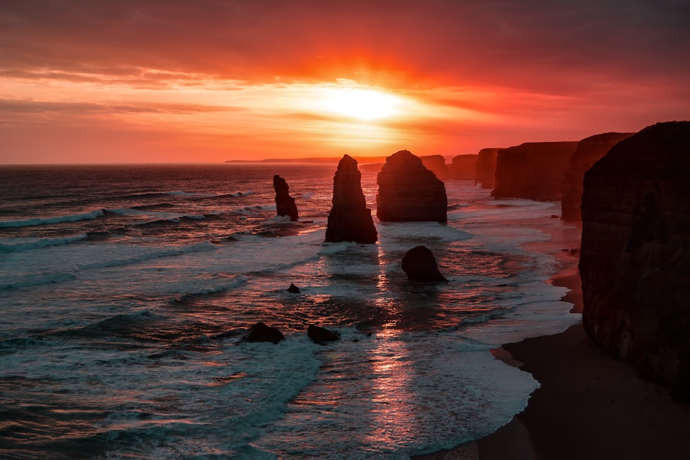 silhouette of stone on seashore during golden hour