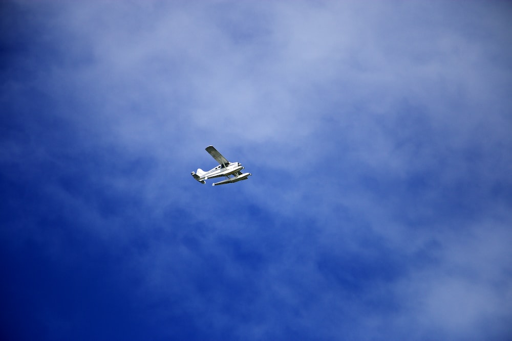 white flying biplane during white and blue sky