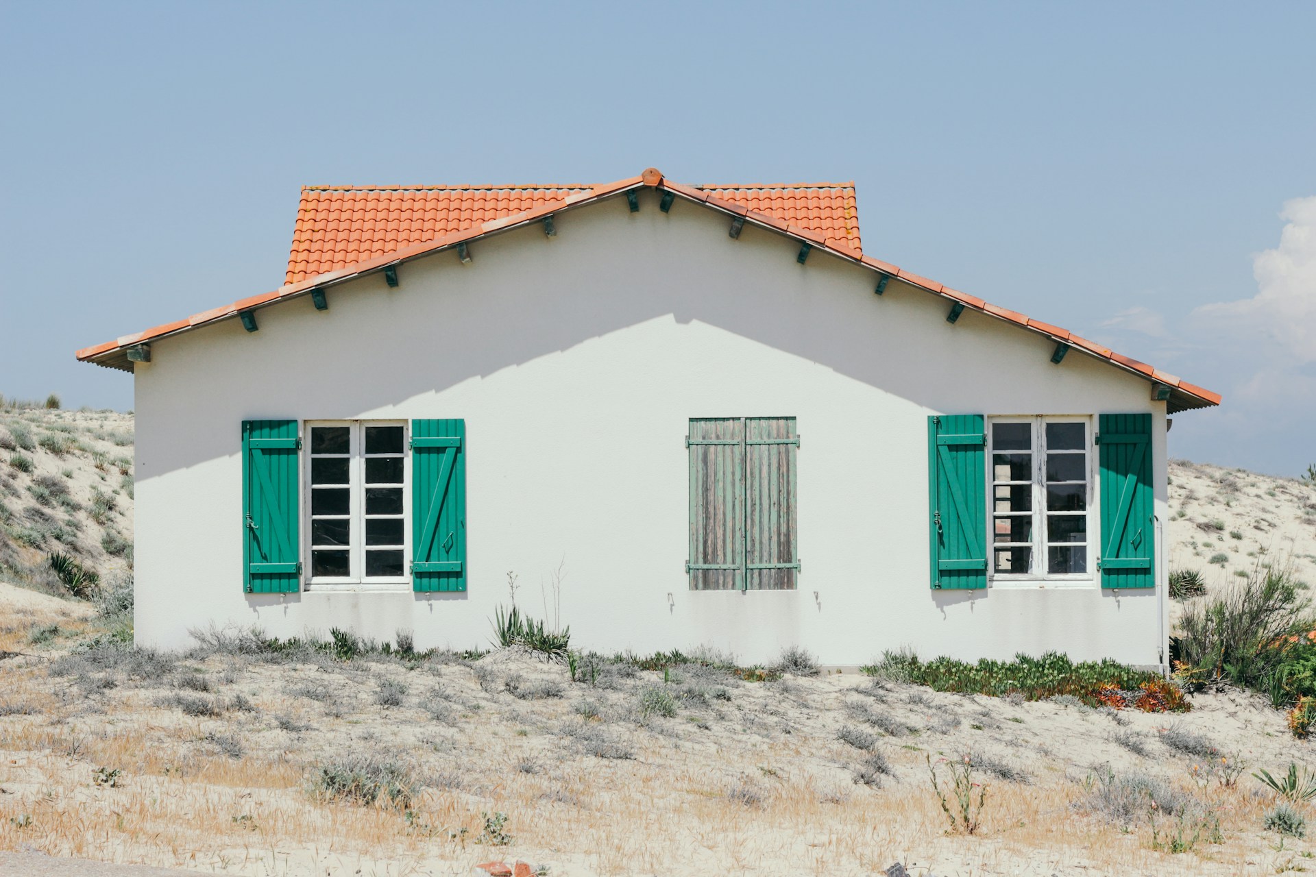 white and green concrete house with windows open at daytime