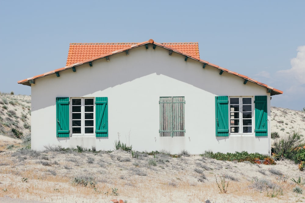 Casa in cemento bianco e verde con finestre aperte di giorno