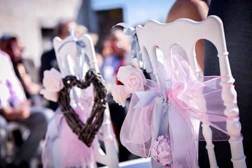 A sweetheart chair setup with black and white linens and gold detailing at an outdoor wedding.