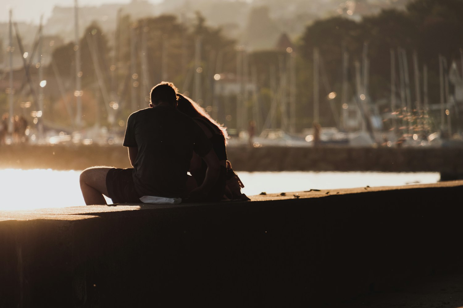 Image of two people embracing, facing a harbor.