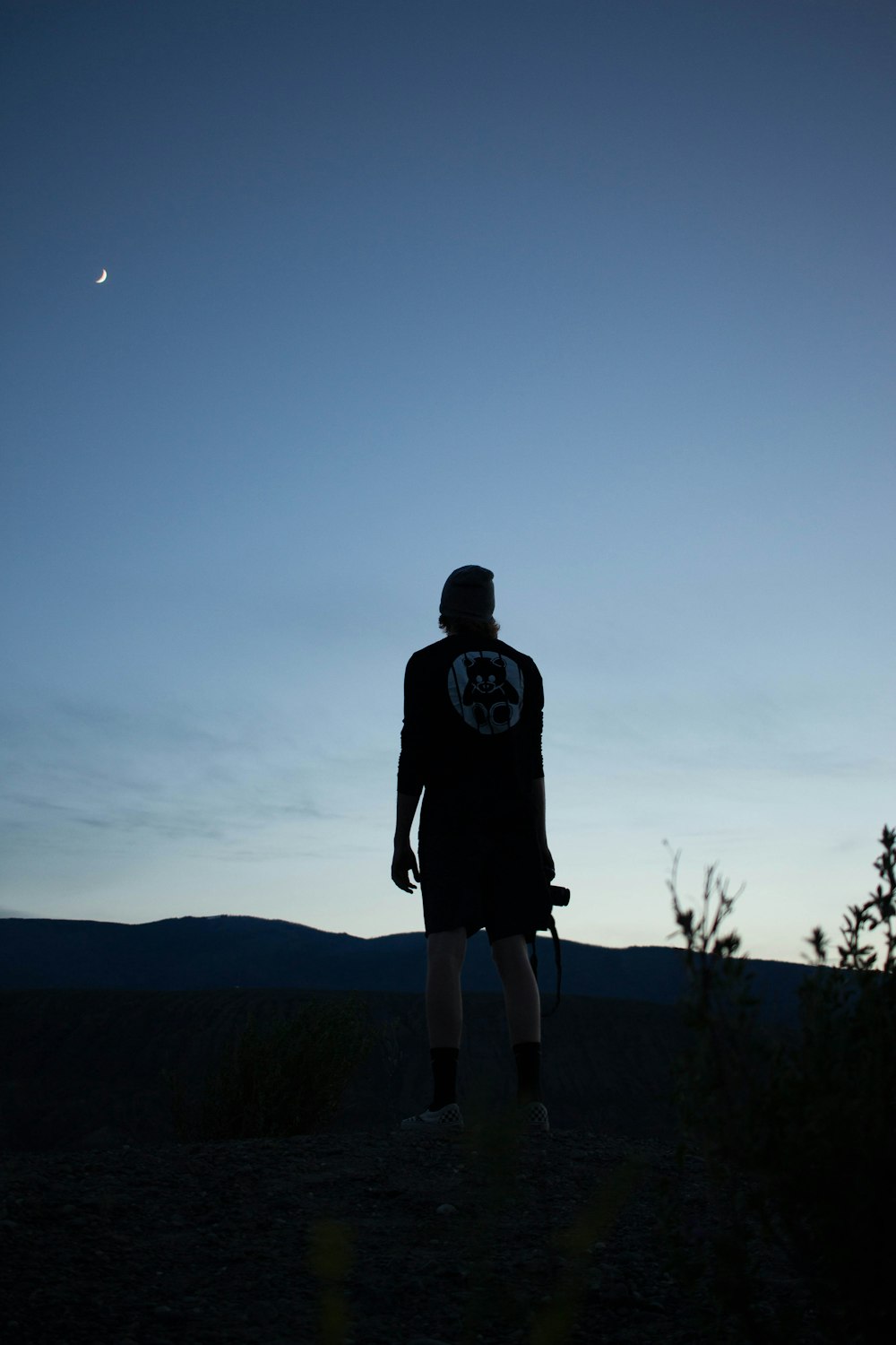 Mann im schwarzen Kapuzenpullover steht nachts auf einem Hügel