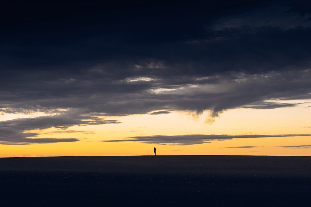 Silueta de la persona de pie en la colina durante la puesta del sol