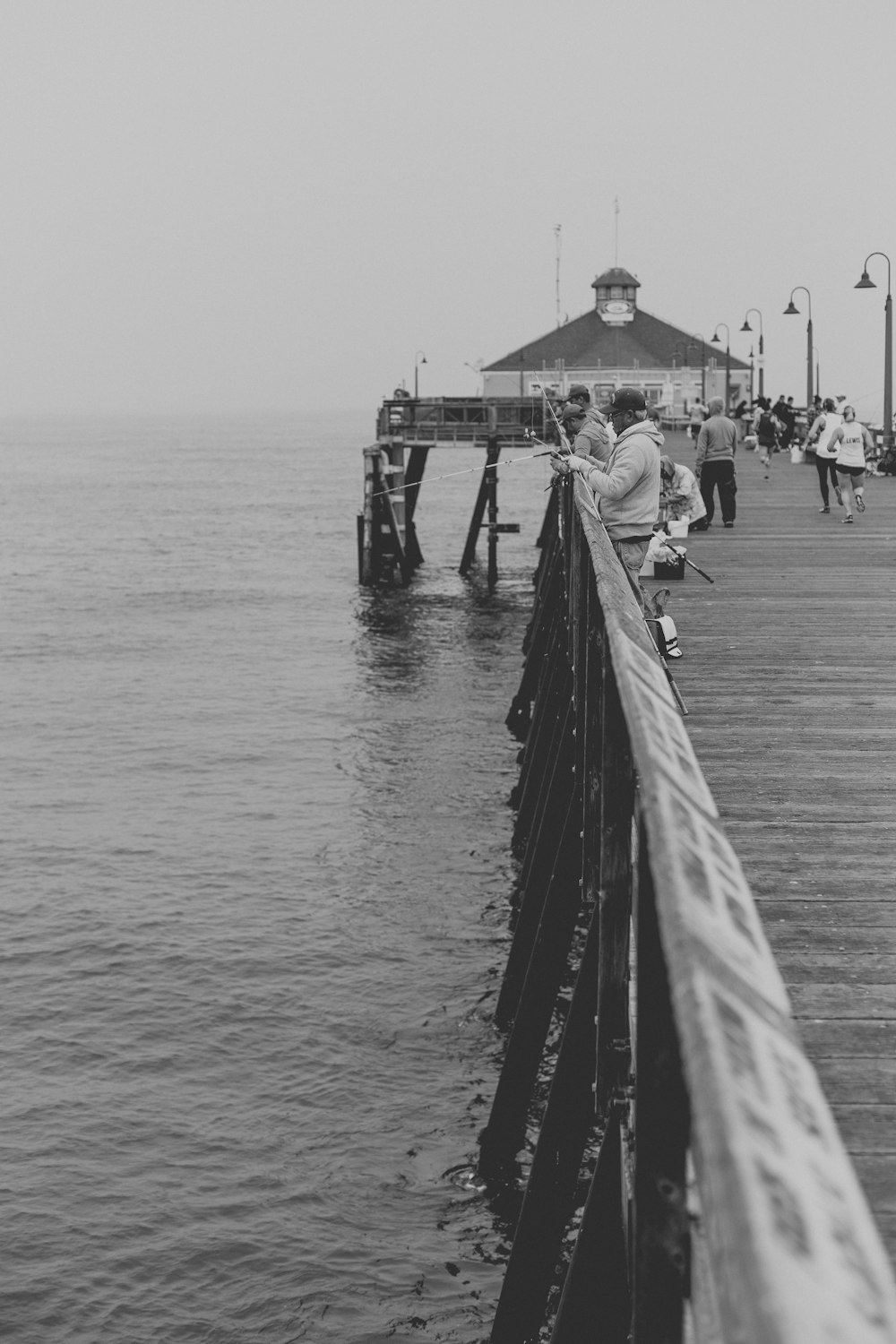 Photographie en noir et blanc de personnes pêchant sur une jetée à Imperial Beach