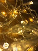 Close-up of cozy lights casting a warm glow over a rustic wooden table.