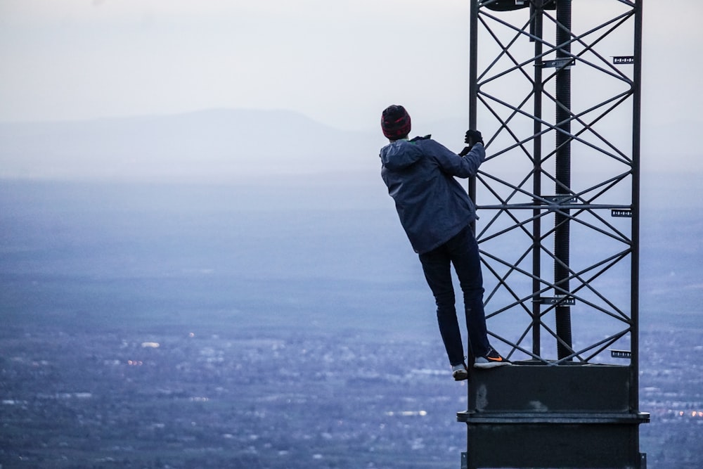 hombre subiendo en la torre cerca de los edificios durante el día