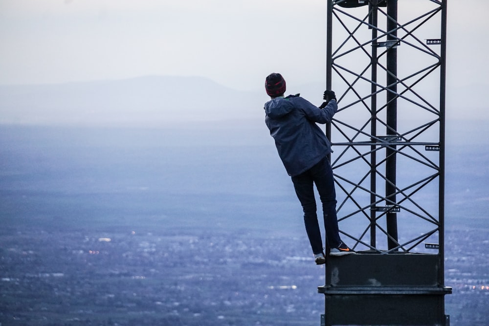 homem escalando em torre perto de edifícios durante o dia