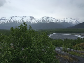 A scenic landscape of snow-capped mountains with a river flowing through a lush valley.
