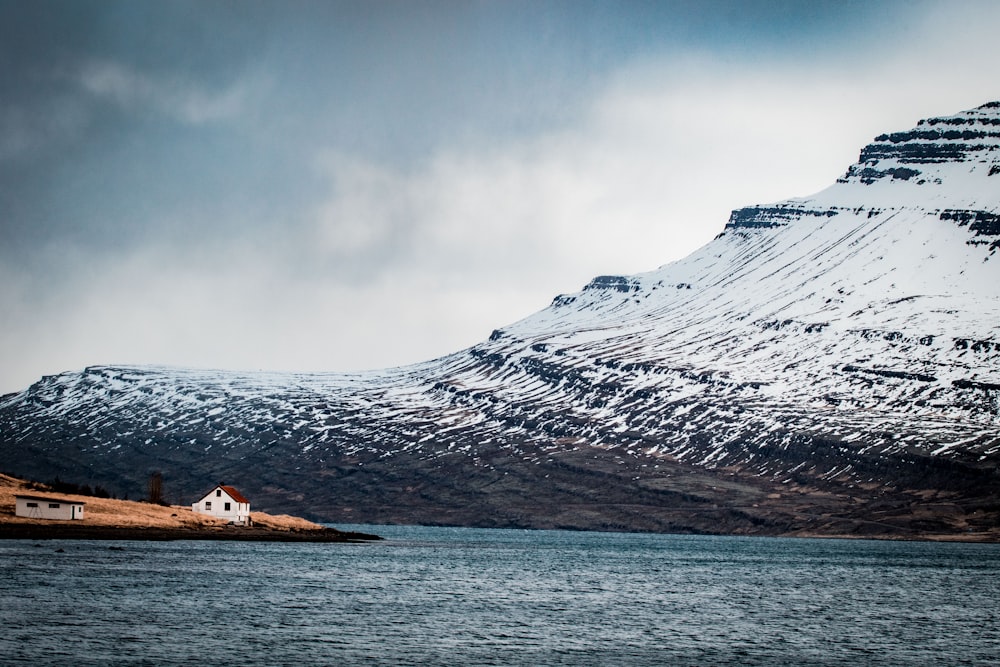 Haus auf Insel in der Nähe eines schneebedeckten Berges am Tag