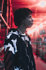 Close-up of a black hoodie with sharp neon green accents under moody industrial lighting.