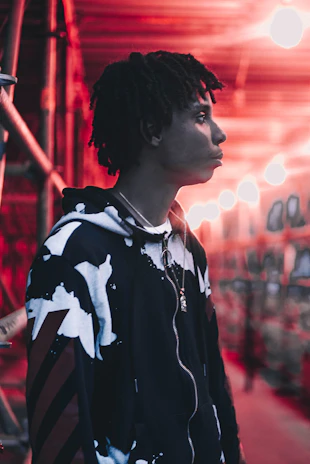 Close-up of a black hoodie with sharp neon green accents under moody industrial lighting.