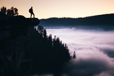 A smiling person standing on a cliff enjoying a breathtaking sunrise, symbolizing new beginnings.