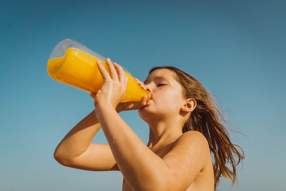 menina bebendo suco amarelo