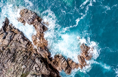 rock mountain next to ocean water drone view google meet background