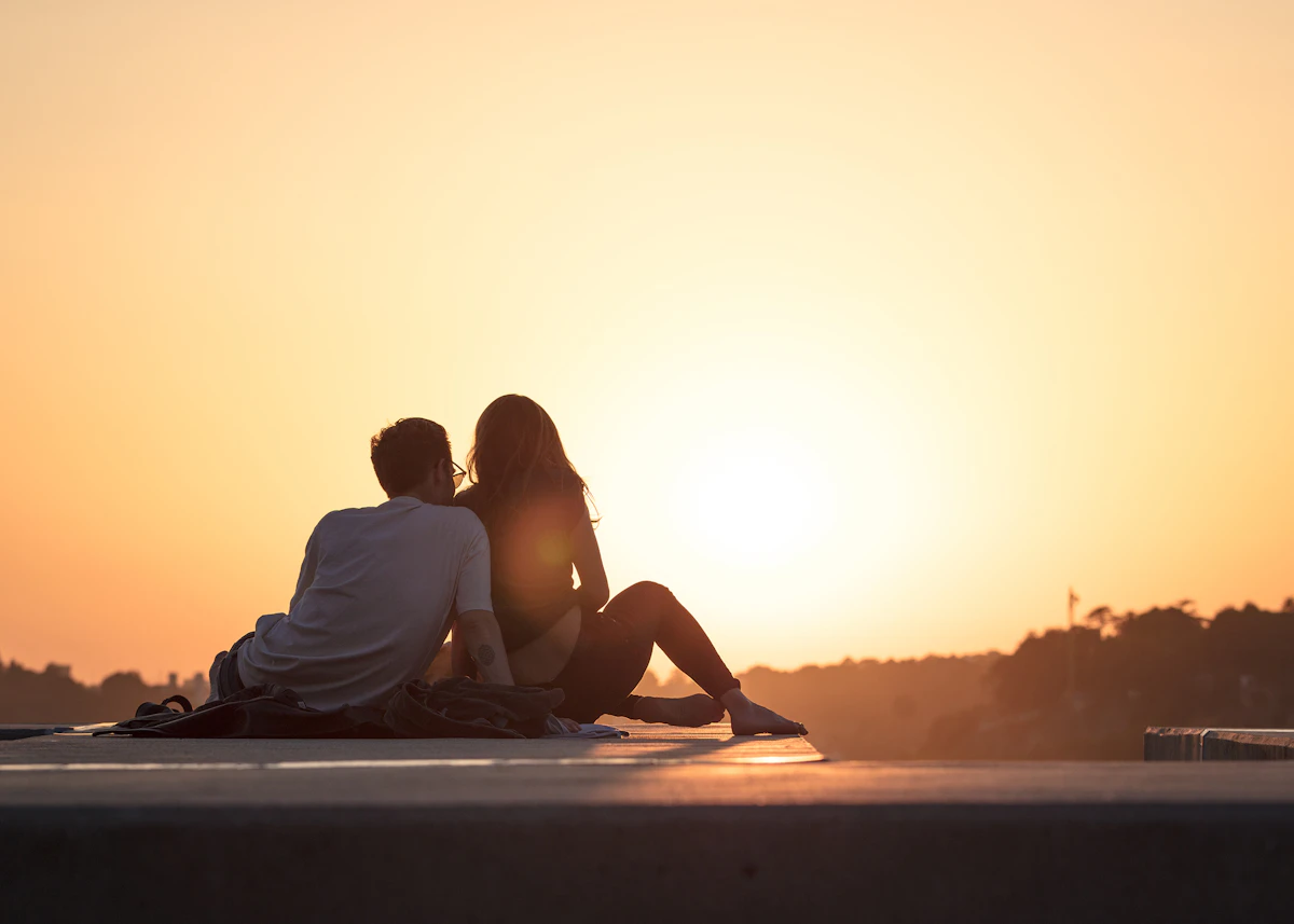 Un couple assis face au coucher de soleil
