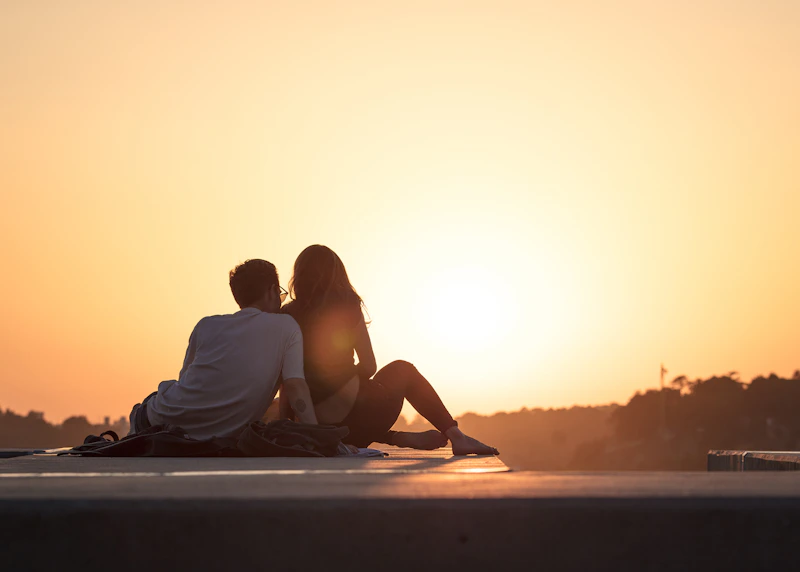 couple sitting peacefully near trees at sunset