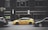 A yellow taxi is parked on the street between two black cars in front of a large building with dark windows. The building has signage for the Hard Rock Hotel and another sign advertising Jamaican cuisine. A vertical light fixture decorates the facade, and there are no visible reflections in the windows.