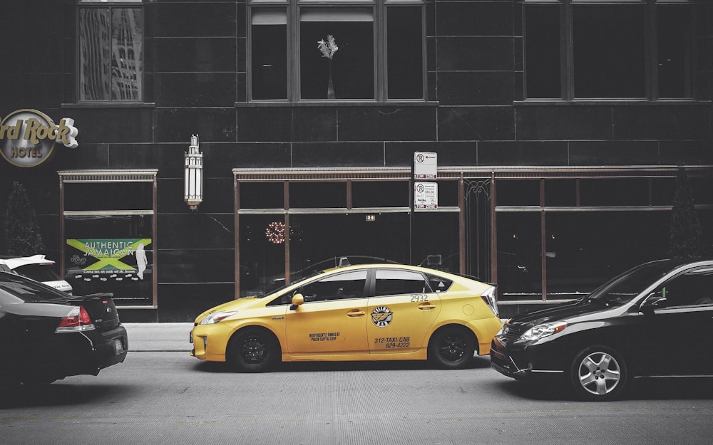 yellow sedan in front of brown building