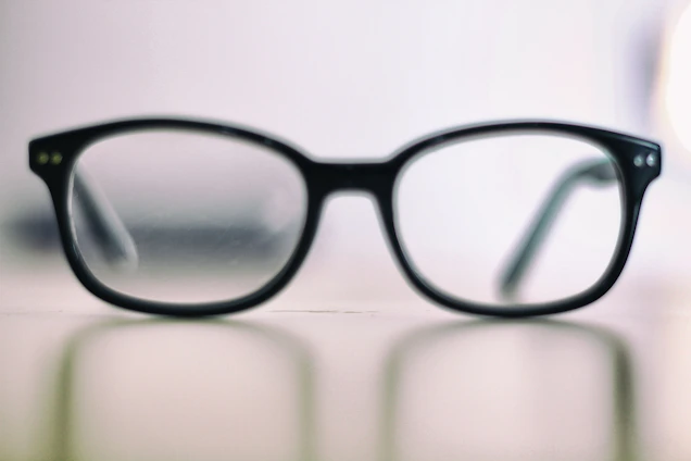Elegant minimalist image of a person wearing stylish glasses with a soft dark background.