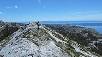 Traveler with backpack enjoying panoramic mountain views under a clear blue sky