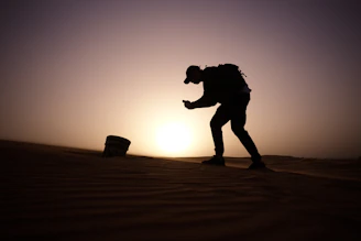 Traveler holding a phone with a weekly Qatar eSIM plan activated, standing near a desert dune at sunset