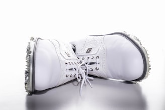 Close-up of premium golf shoes and gloves arranged neatly on a wooden bench.