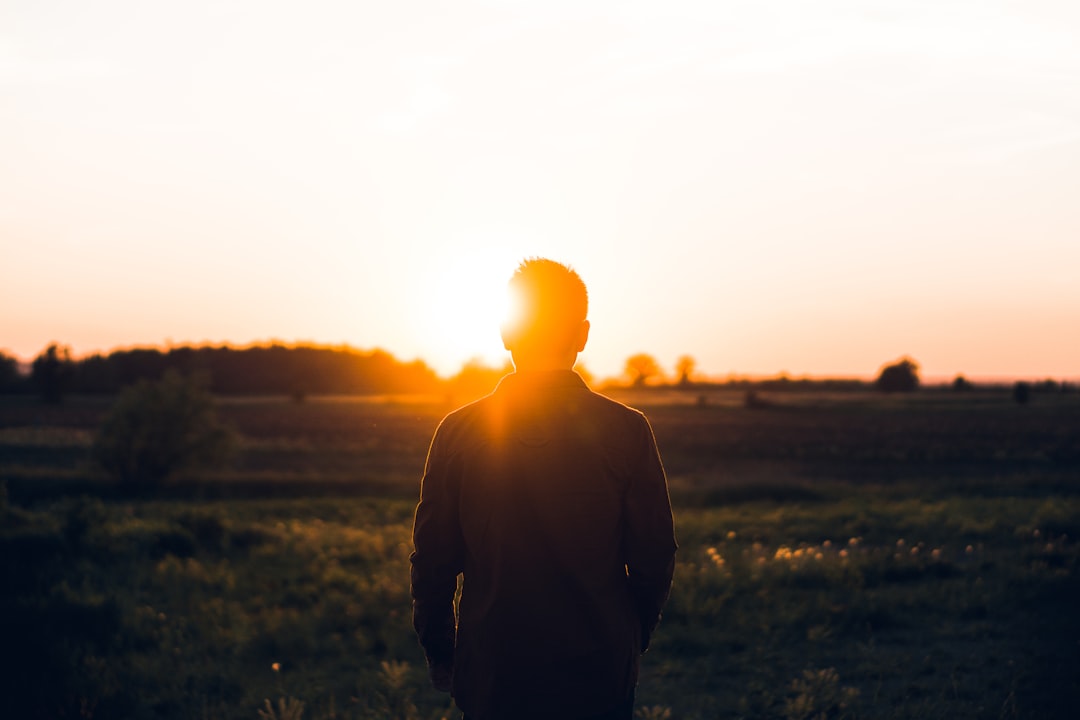 silhouette of man facing sunset,