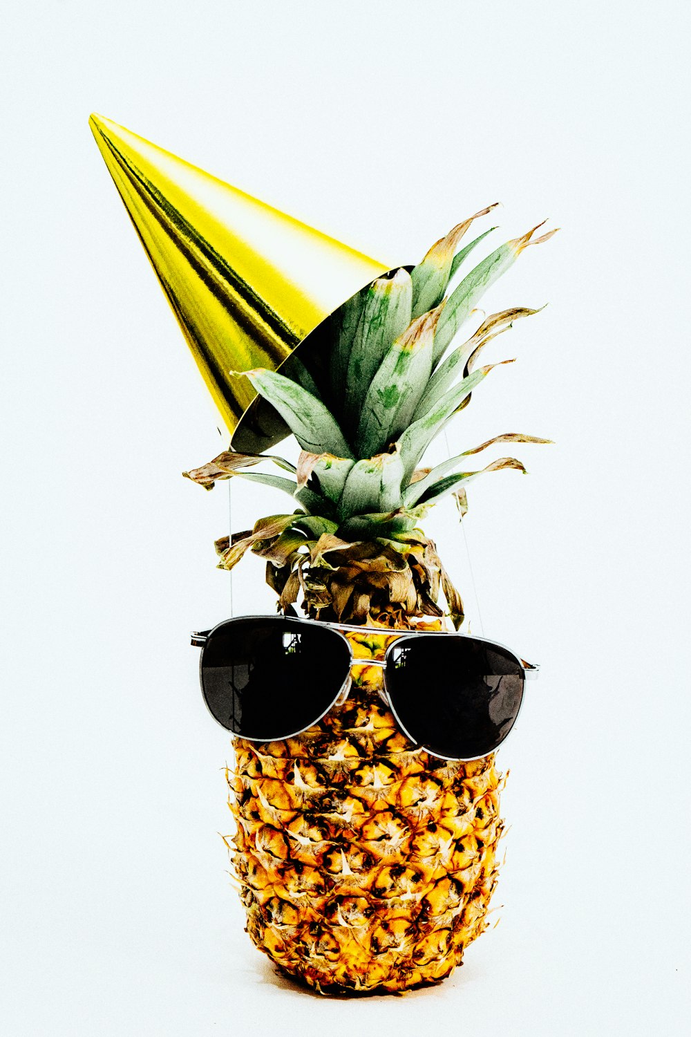 ananas maturo con cono giallo e occhiali da sole