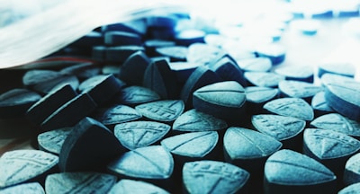 Close-up of blue chemical powders and capsules on a lab bench.