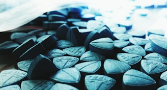 Close-up of assorted 7-hydroxymitragynine tablets in various colors and sizes.